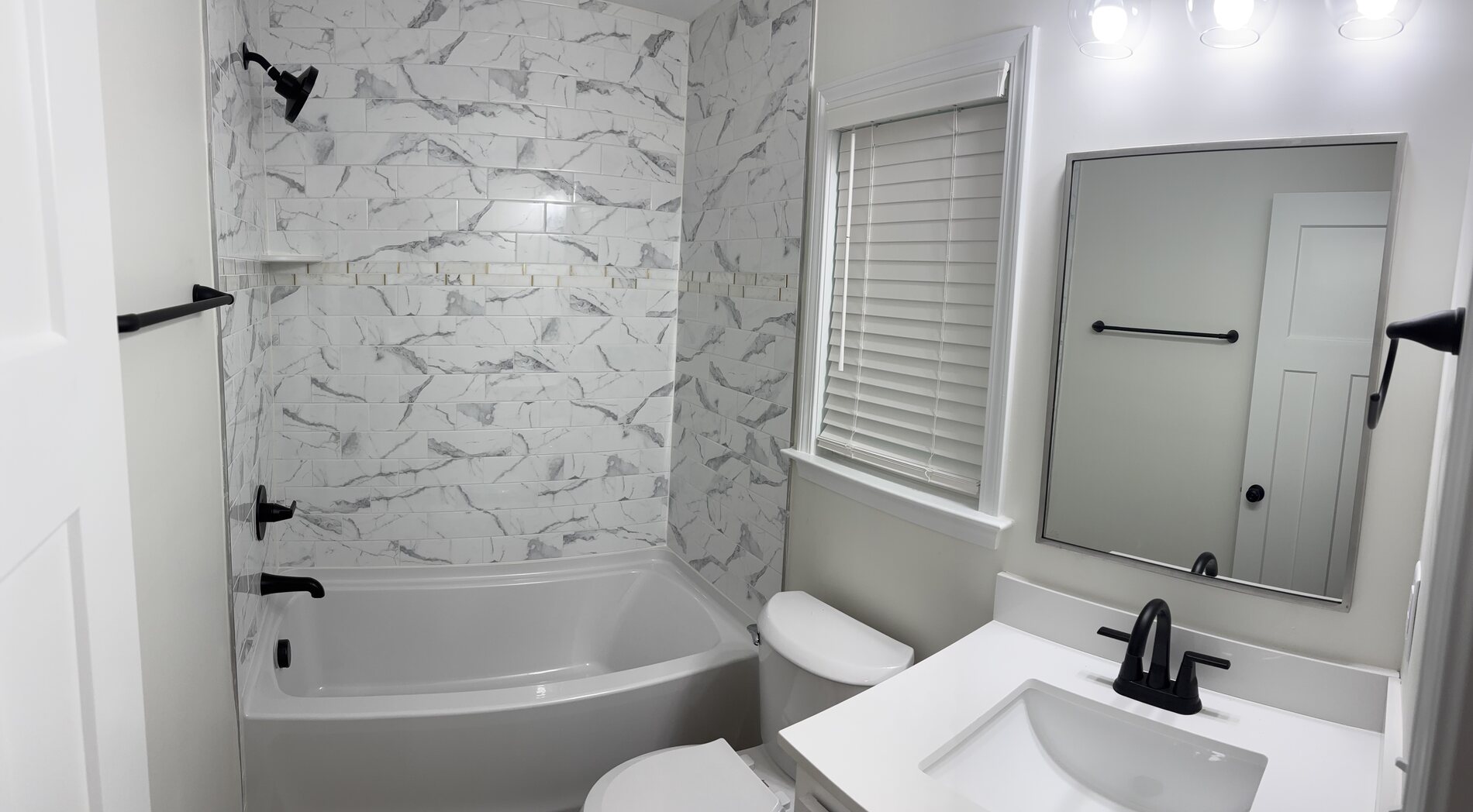 Full bathroom with a tub, marble effect tile and matt black fittings