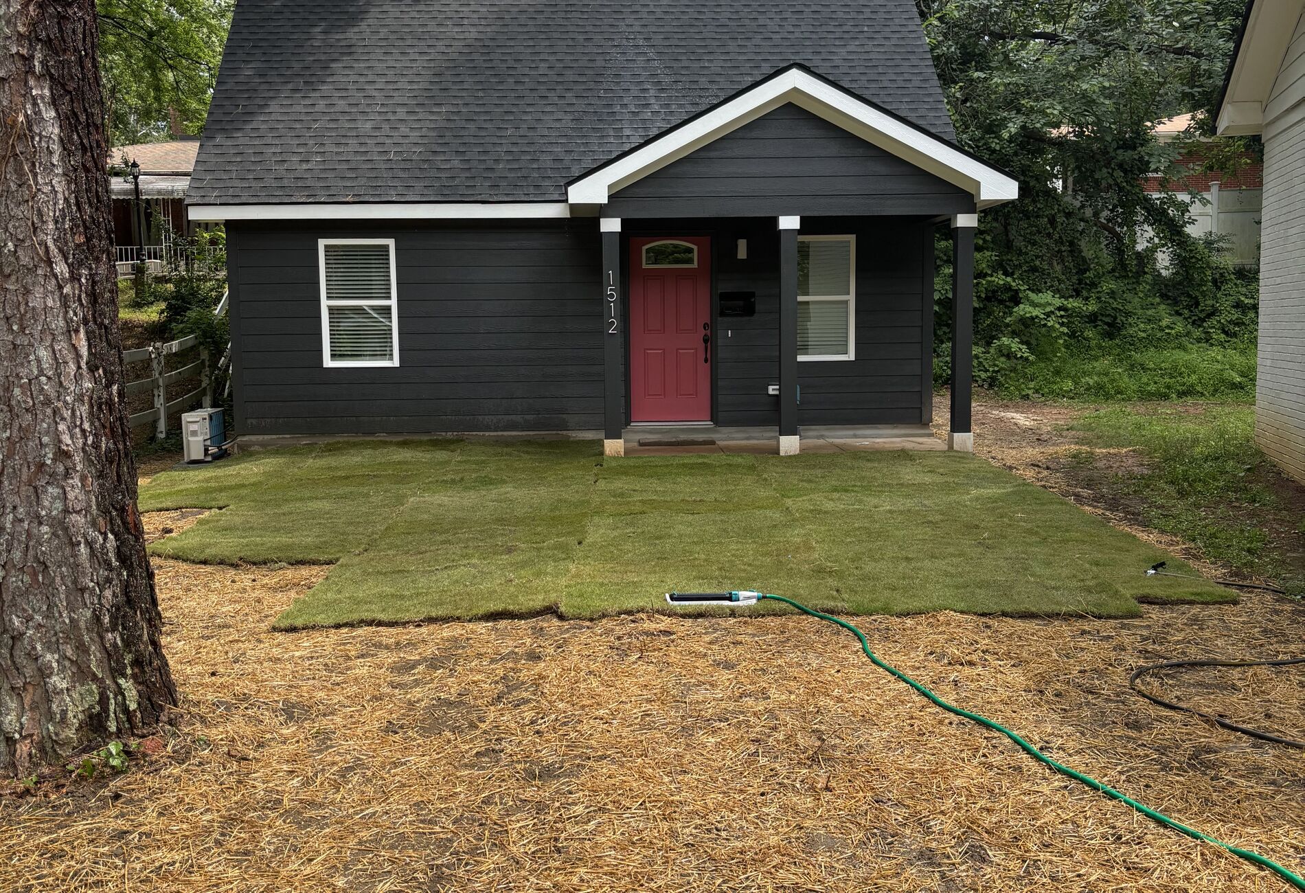 Charcoal accessory dwelling unit with a red front door in a downtown Raleigh yard