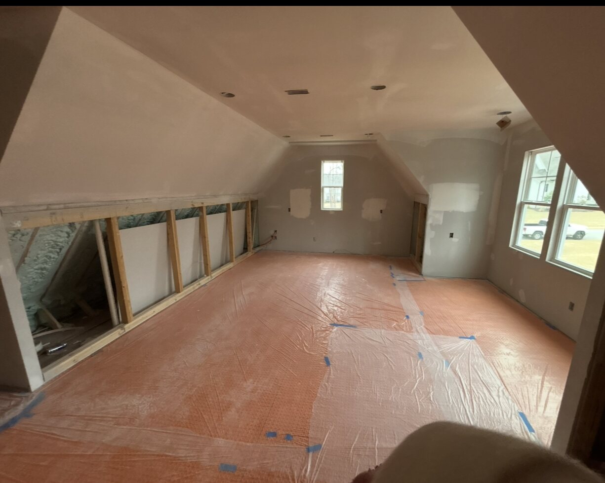 The room drywalled and primed with the floor protected