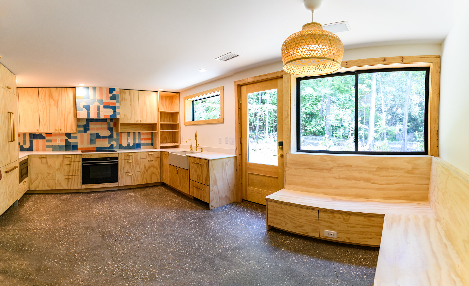 Wide view of the custom kitchen with a rattan pendant, built in window seat and picture window